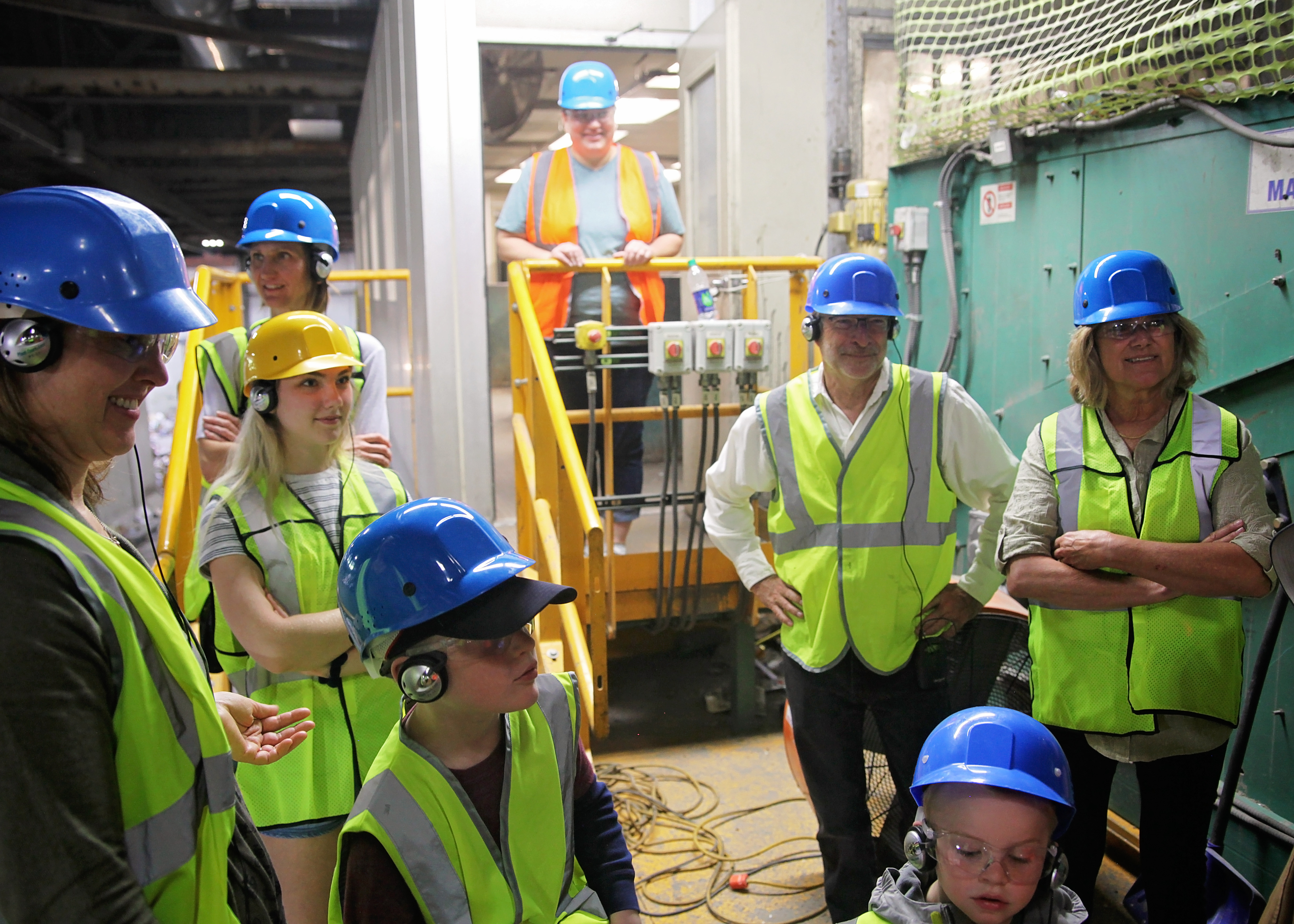 People in hard hats and reflective vests listen on a tour of Eureka's recycling facility.