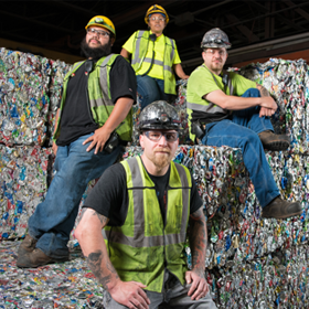 Group of Eureka staffers pose by blocks of compressed waste.